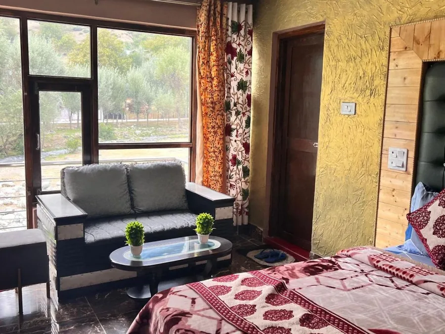 Seating area by the river-facing window in a Deluxe Room with balcony at Hotel Seven Pahalgam