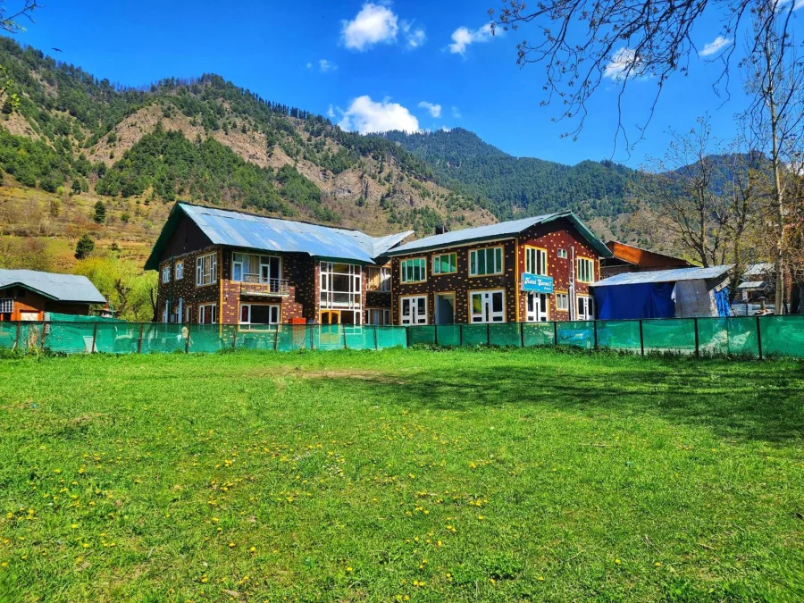 Exterior of Hotel Seven Pahalgam with its lawn and the hillside behind