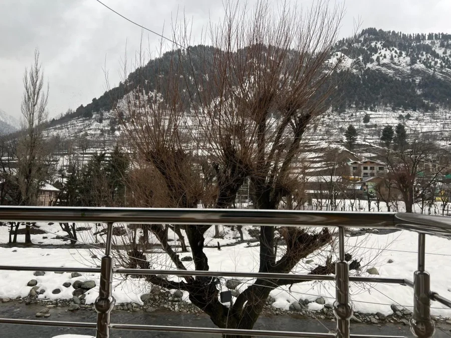 View from a balcony at Hotel Seven Pahalgam over snow-covered ground and hills